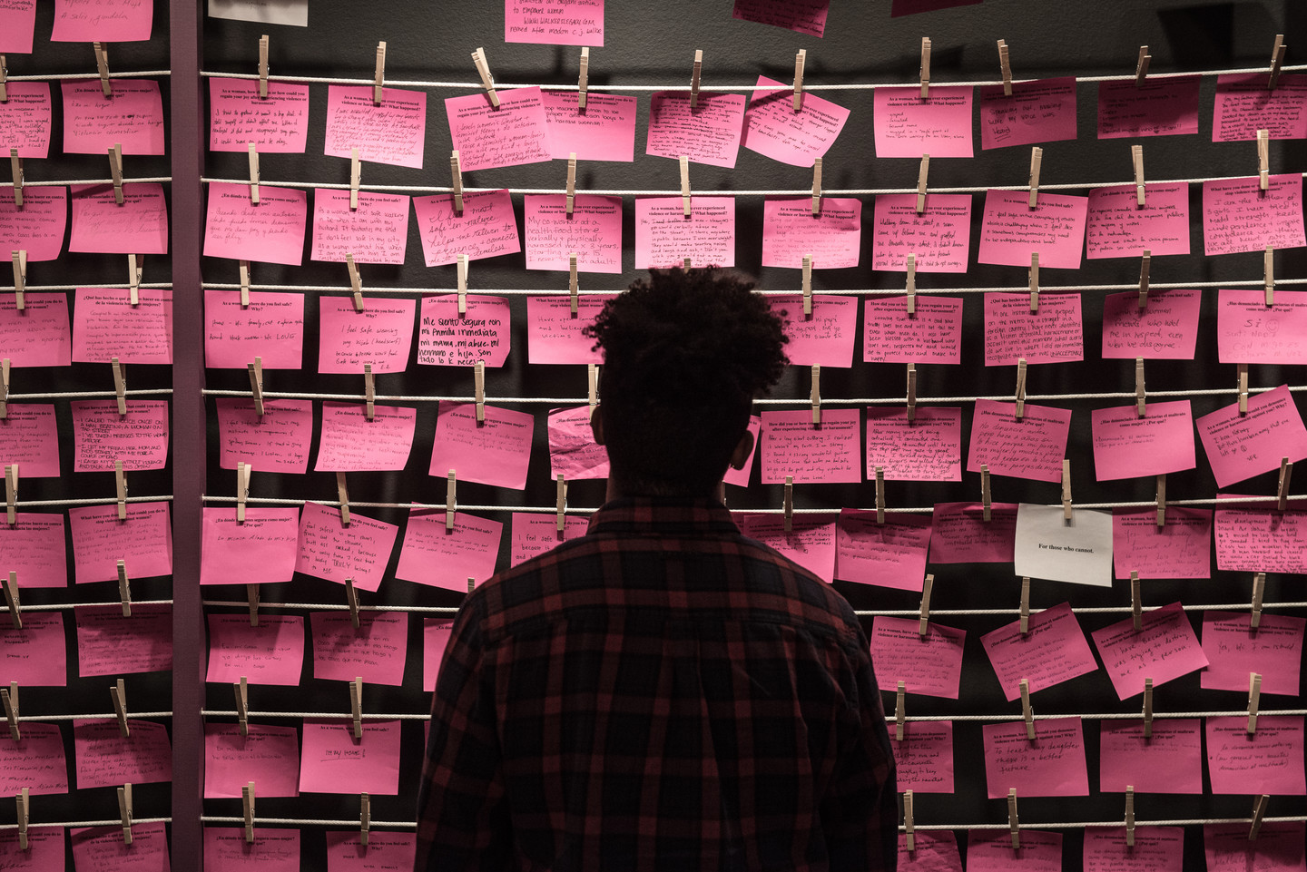 Man stands in front of rows of hot pink post-it notes.