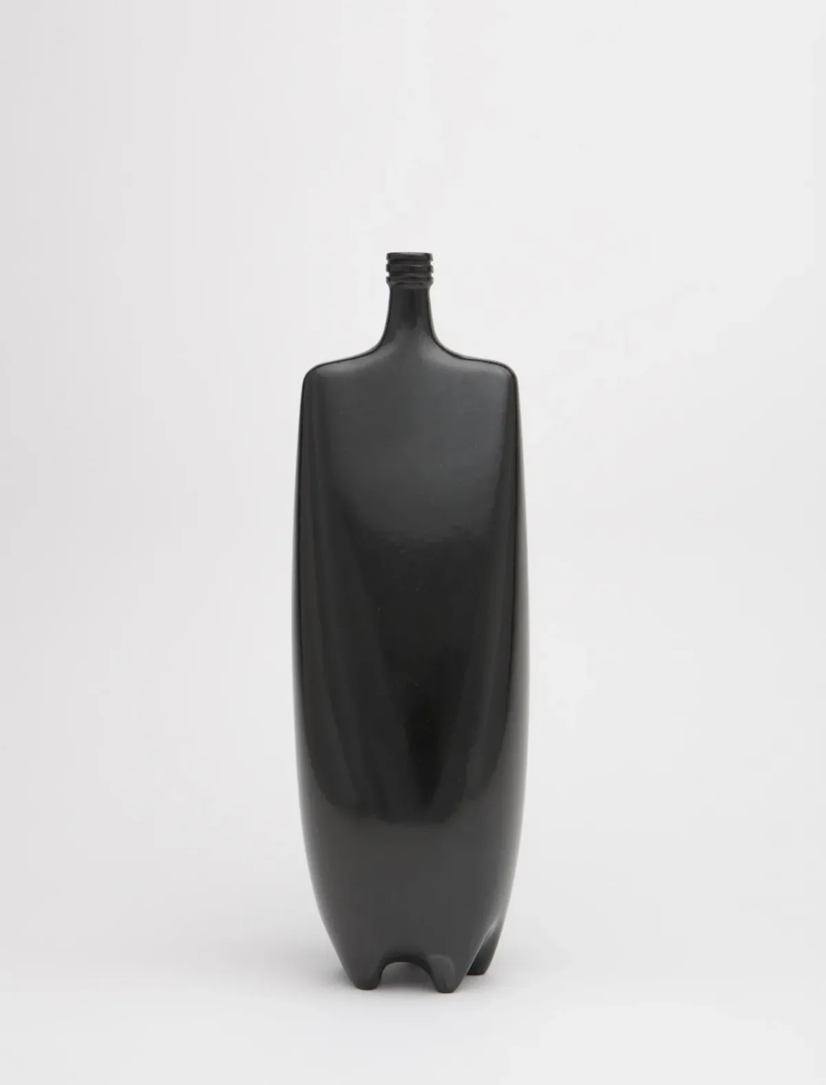 Shiny, black sculpture made of clay resembles a bottle with a square top and rounded body.