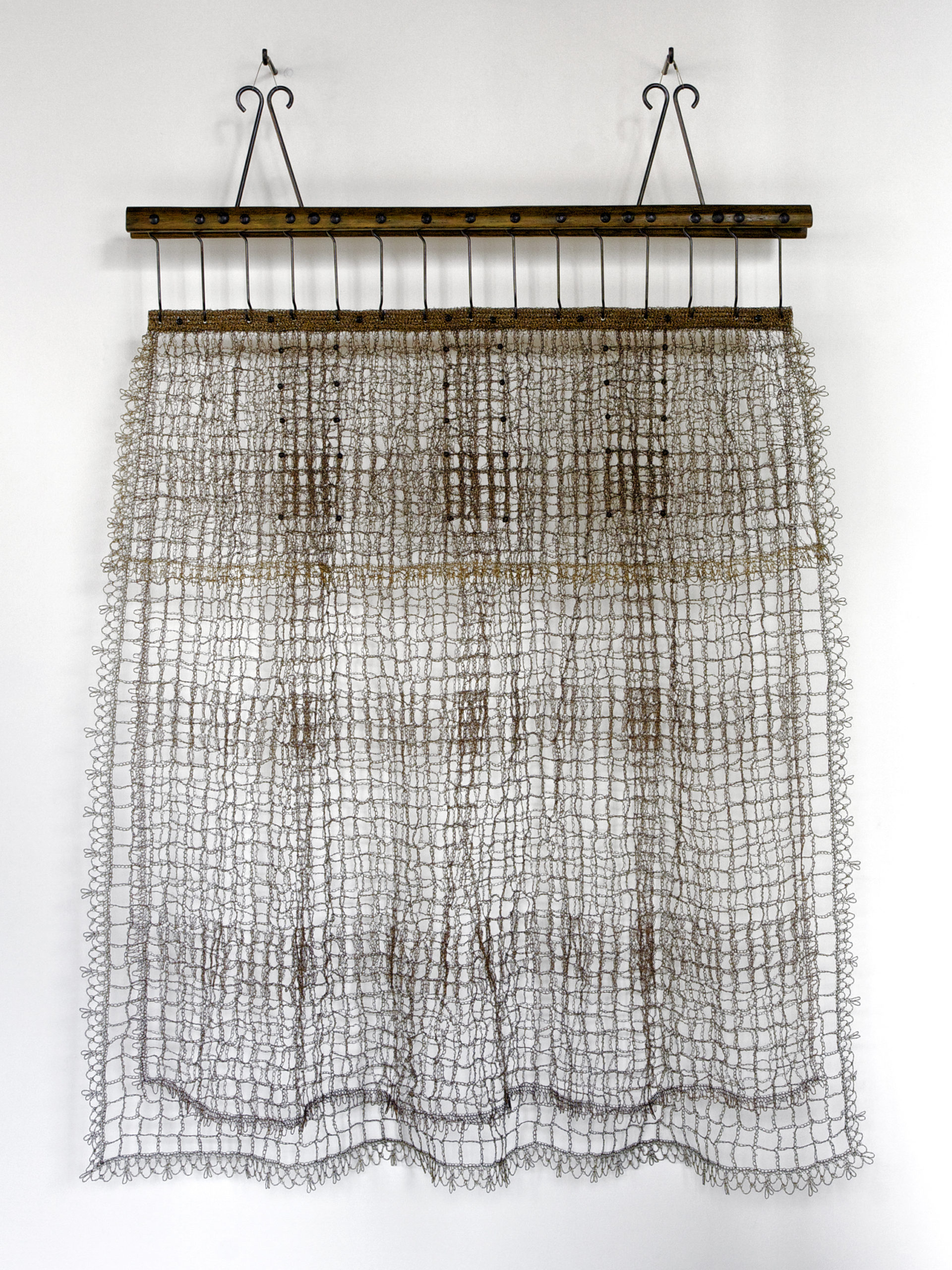 Crocheted wall hanging made of two horizontal wood bars at the top secured with two nails.