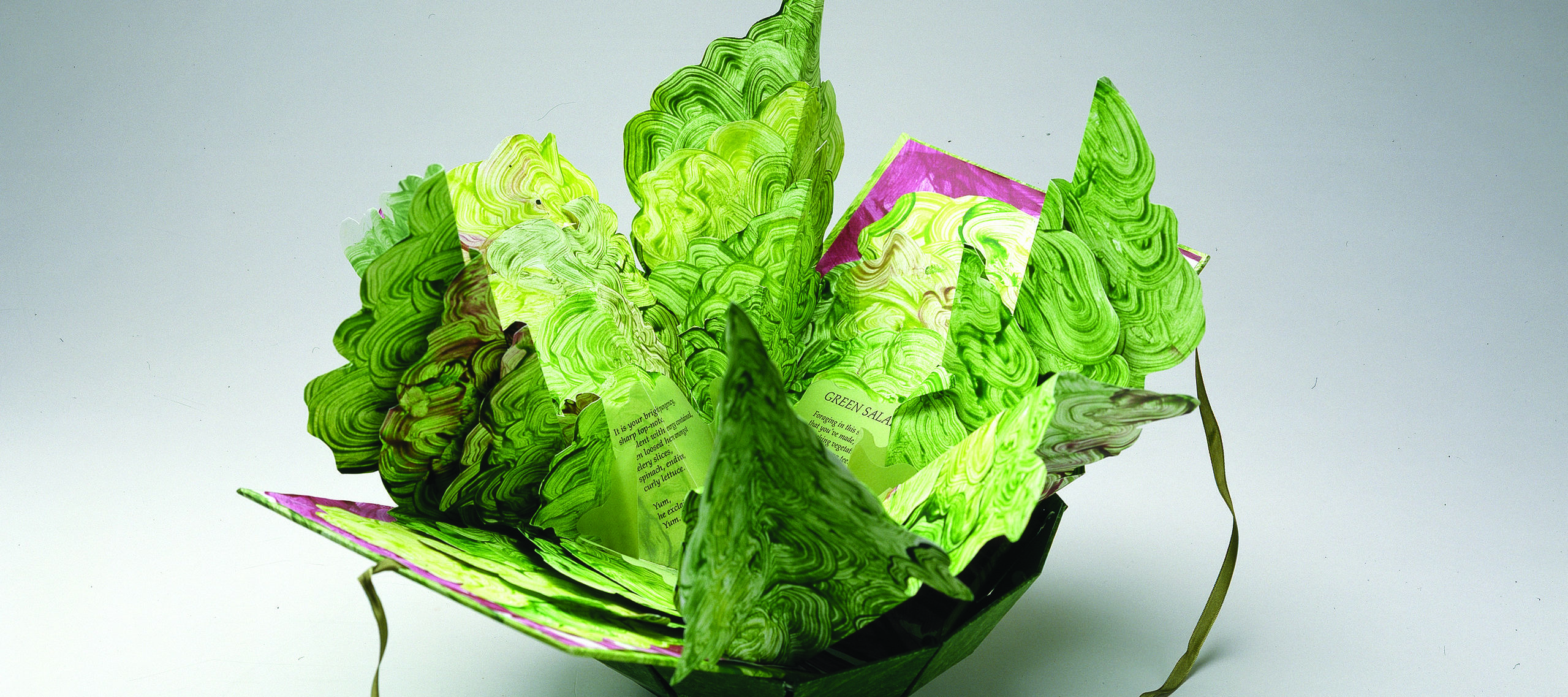 Artist's book resembling a salad in a bowl. Constructed of Tyvek that has been painted in swirling greens and map-folded to look like leaves of lettuce, there is poem written on the inner the leaves.