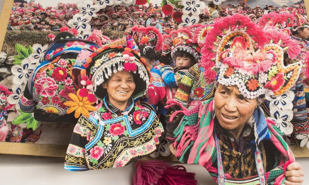 Large-scale pop-up book depicts the culture and traditions minority areas in China by showing numerous people in brightly colored, traditional dress.