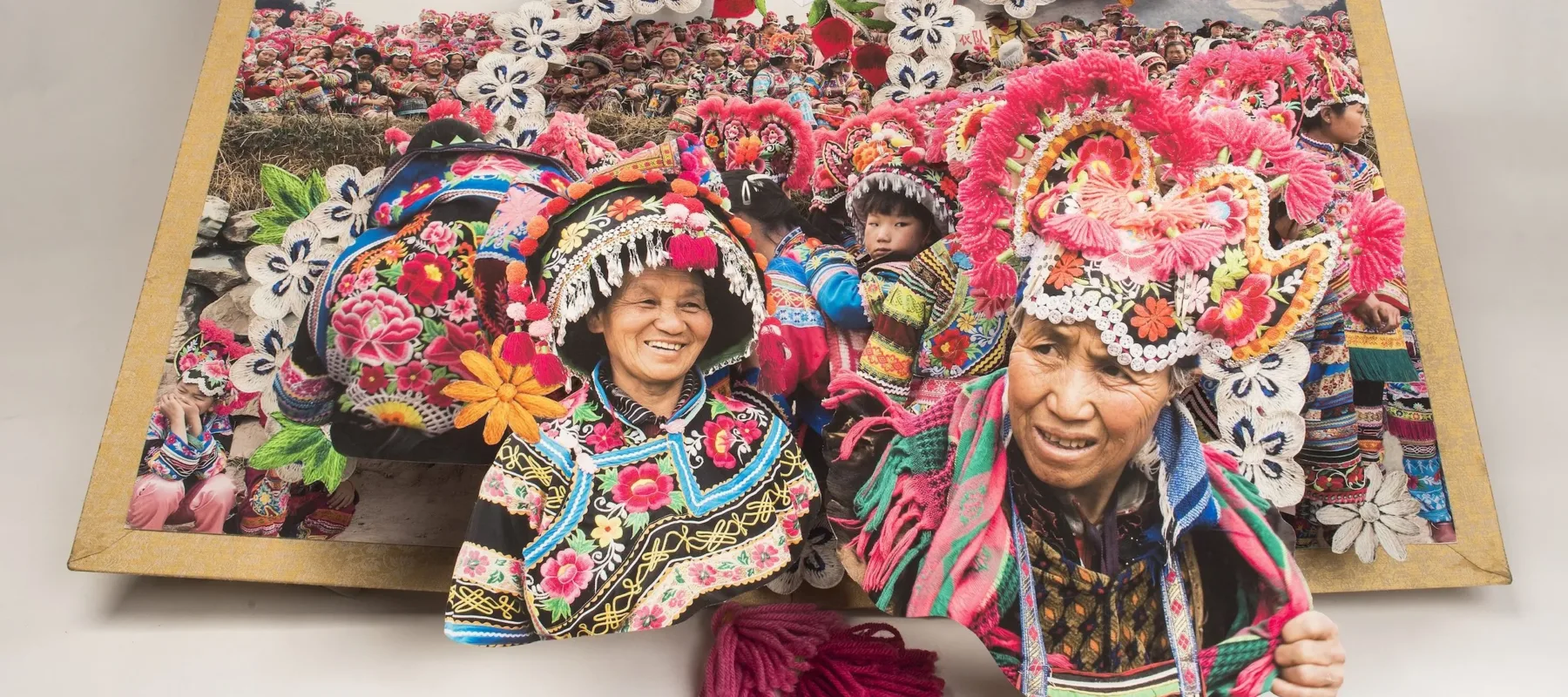 Large-scale pop-up book depicts the culture and traditions minority areas in China by showing numerous people in brightly colored, traditional dress.