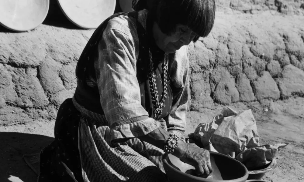 Black and white photograph of woman with medium skin tone making pottery.