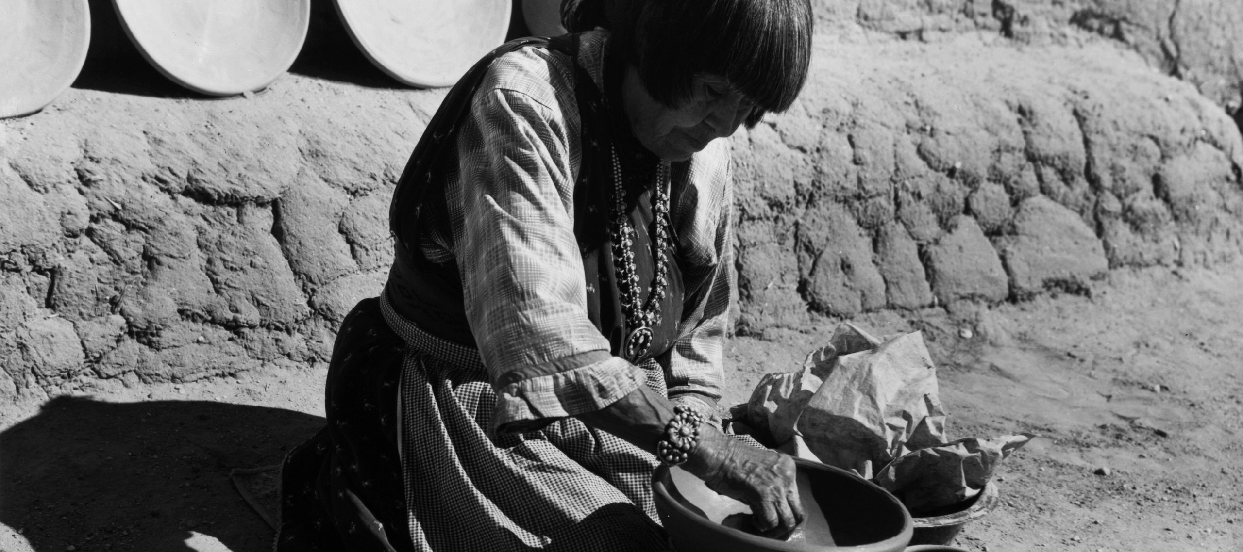 Black and white photograph of woman with medium skin tone making pottery.
