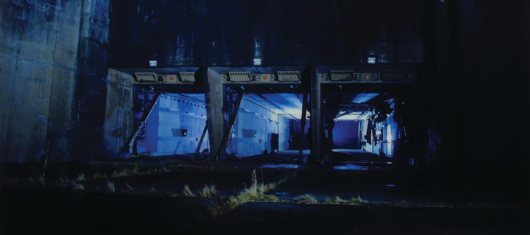 Eery photograph in blue tones of a concrete silo at night.