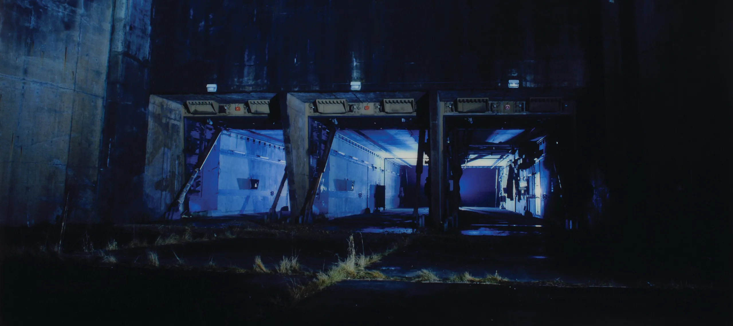 Eery photograph in blue tones of a concrete silo at night.