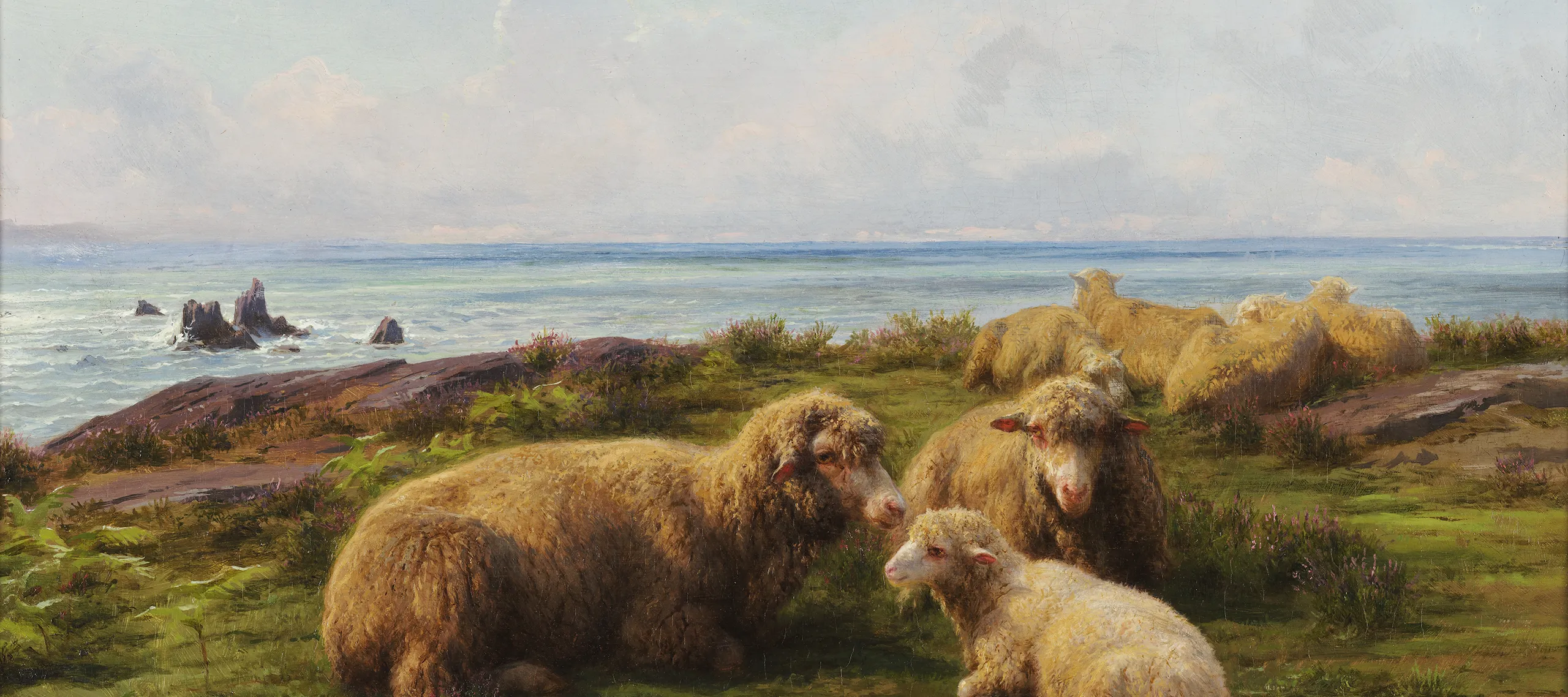 A flock of sheep rest on a green hill by the sea. In the center, two adults and a lamb lie in a group. Flat rocks are visible through the grass. The sky has rolling clouds, and a breeze is suggested by the waves crashing on rocks in the sea, which stretches to the horizon.