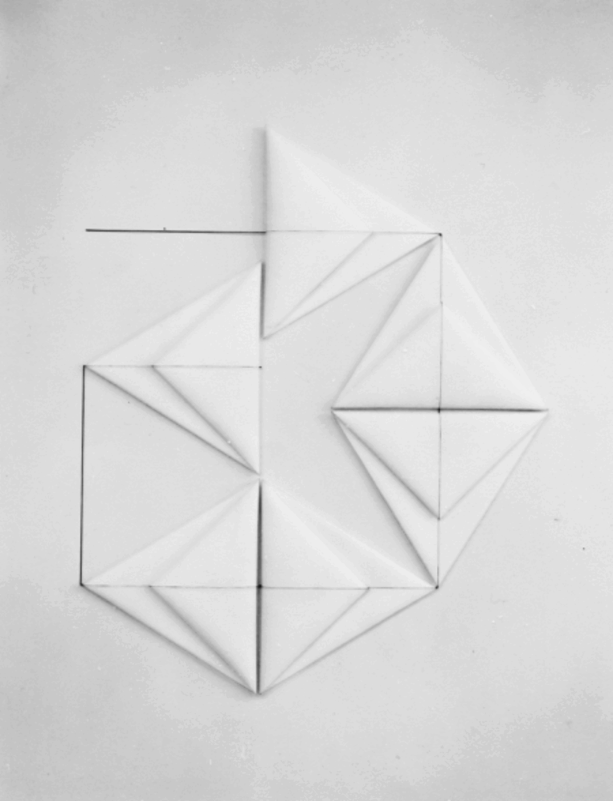Six folded white triangles resembling origami form a large geometric shape on a white background. Connected by a continuous line that bisects their center, the corners of each triangle touch and encourage the eye to move in a circular fashion.