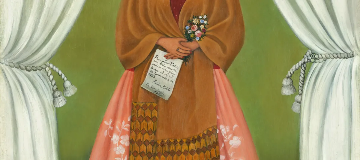 In a painted self-portrait, the artist stands in a stage-like space framed by white curtains. Beneath black hair woven with red yarn and flowers, heavy brows accent her dark-eyed gaze. Clad in a fringed, honey-toned shawl; long, pink skirt; and gold jewelry, she holds a bouquet and a handwritten letter.