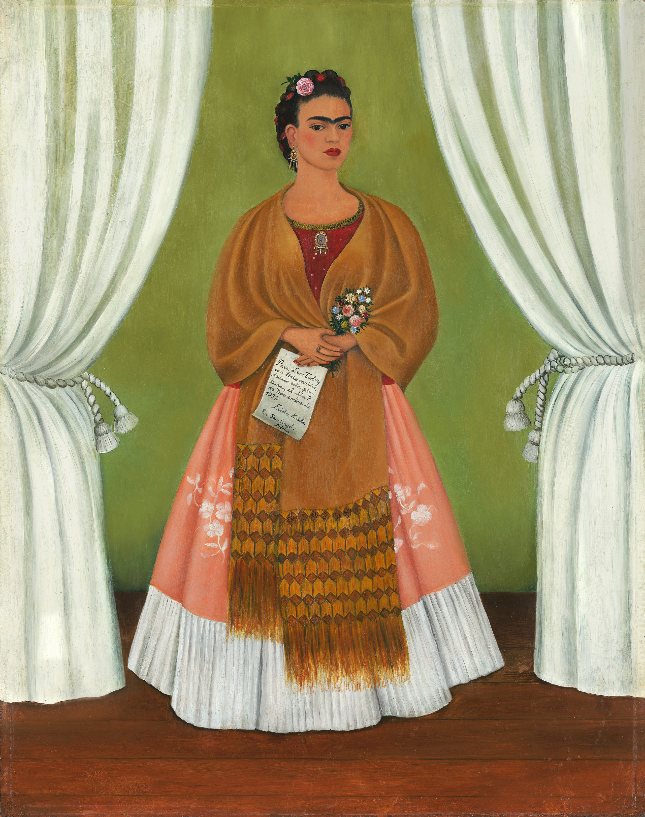 In a painted self-portrait, the artist stands in a stage-like space framed by white curtains. Beneath black hair woven with red yarn and flowers, heavy brows accent her dark-eyed gaze. Clad in a fringed, honey-toned shawl; long, pink skirt; and gold jewelry, she holds a bouquet and a handwritten letter.