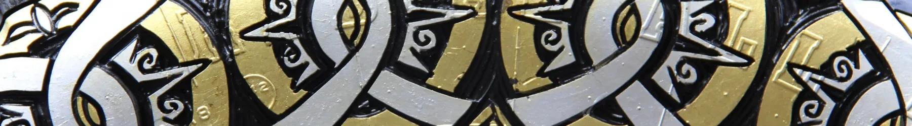 Close-up photograph of a sculpture made of a truck tire carved with circular designs and painted gold and silver