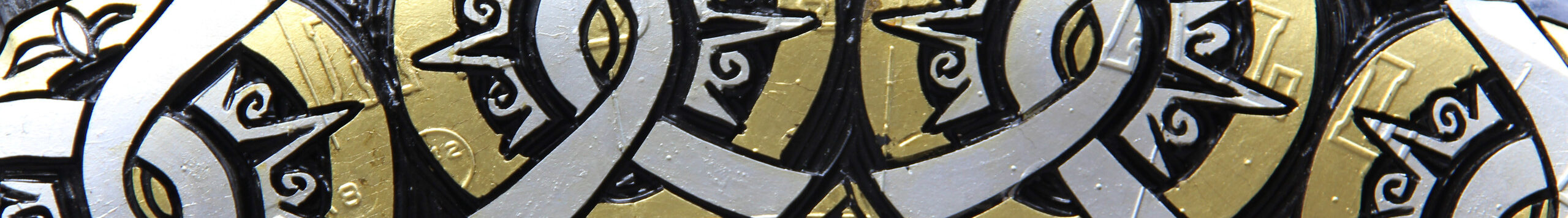 Close-up photograph of a sculpture made of a truck tire carved with circular designs and painted gold and silver