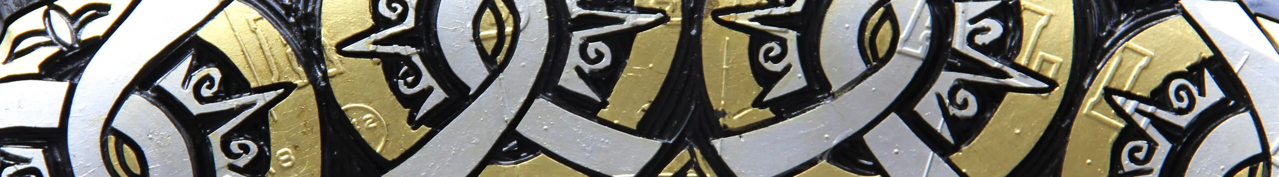 Close-up photograph of a sculpture made of a truck tire carved with circular designs and painted gold and silver