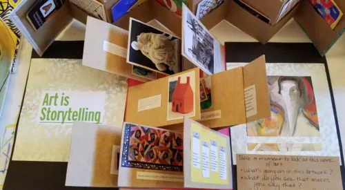 A birds-eyed view of a display of artists books showing a variety of folded paper and works of art.