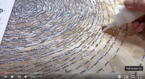 Still frame from a video of Ambreen Butt's hand delicately applying glue to paper to affix cutout words