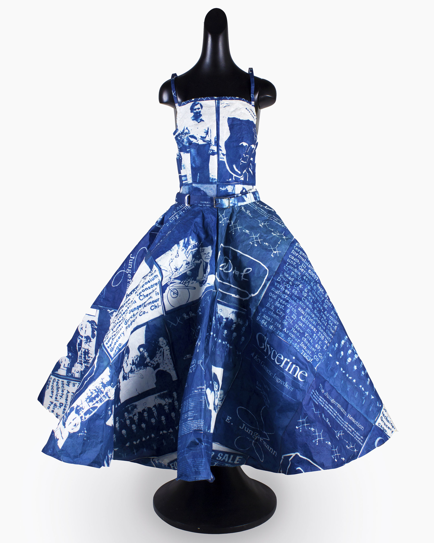 A sleeveless rich blue full-length gown placed on a headless black mannequin with rounded base. The dress has white text and images printed on the surface.