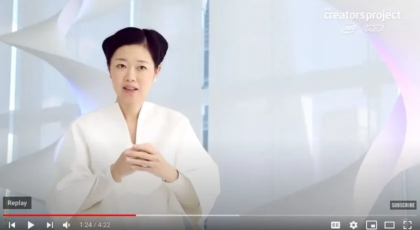 Screenshot of a Youtube video showing a young Japanese woman speaking in a white billowy jumpsuit