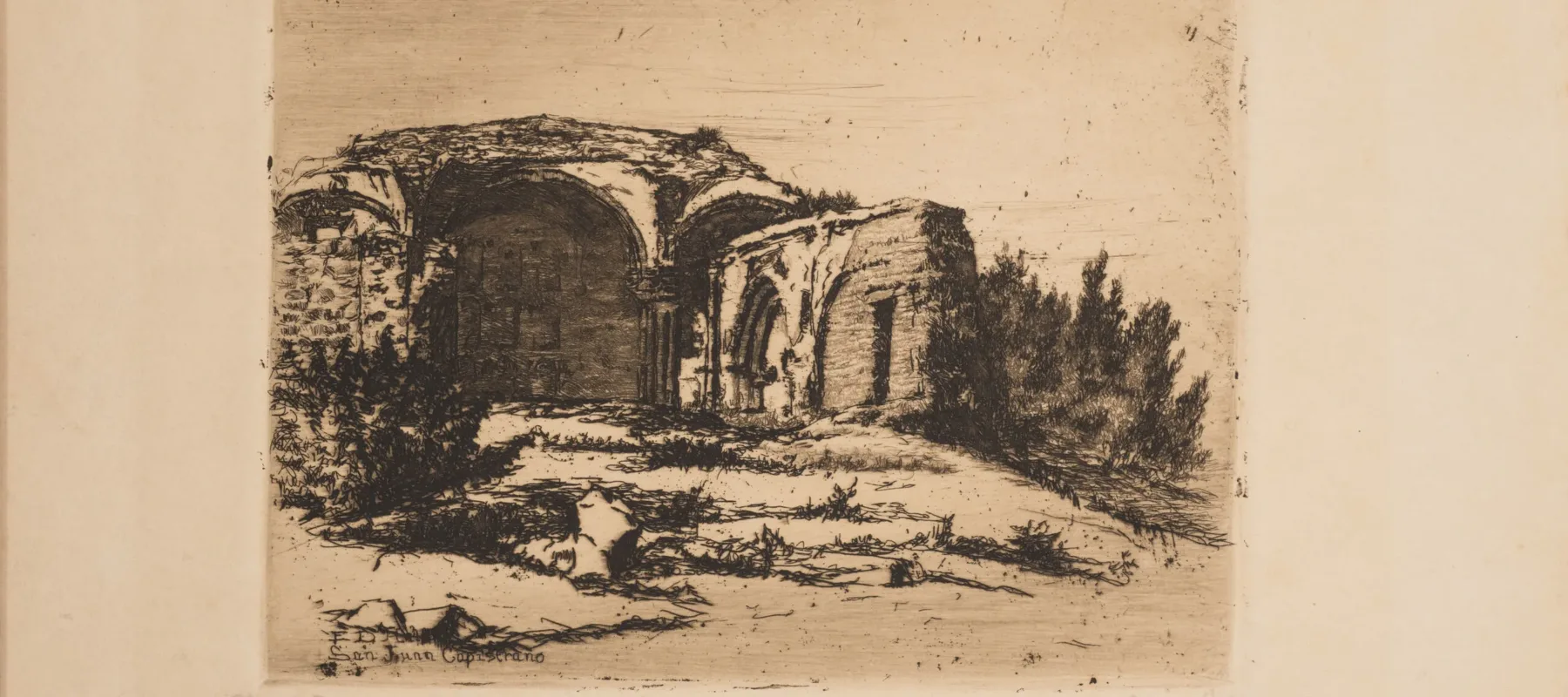 Small print of black ink on ecru paper depicting the ruins of an old Catholic mission building. The building, featuring rounded arches, crumbling facades, and exposed brick, is surrounded by scrub bushes and desert landscape.