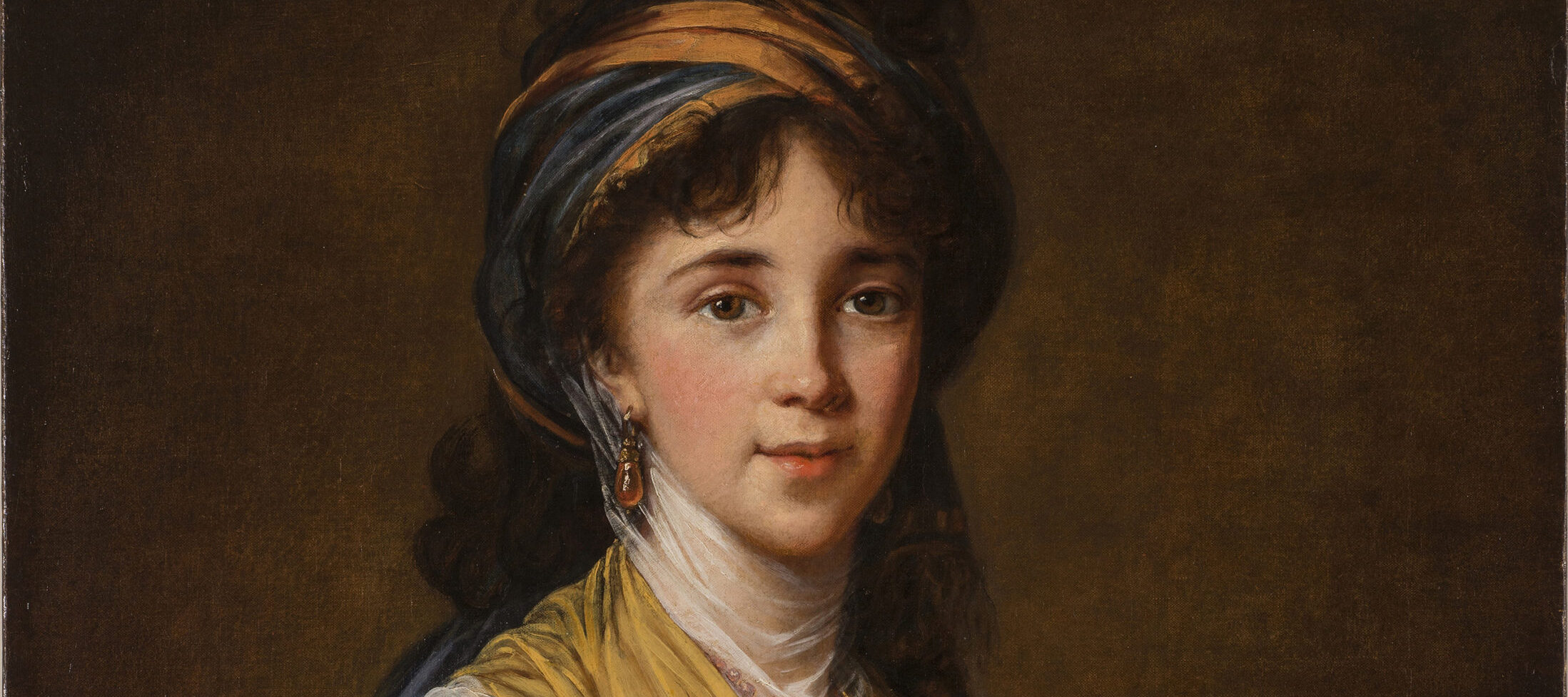 Realistically rendered half-portrait of a light-skinned young woman, gazing directly at the viewer with a faint smile on her lips. Her dark, curly hair is attractively tousled, secured under a turban-like headdress which matches her gold and blue draped ensemble.