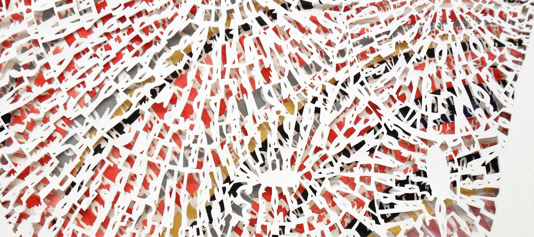 A detail of contemporary paper art with a colorful painted base underneath thousands of cut alphabet letters in concentric designs.