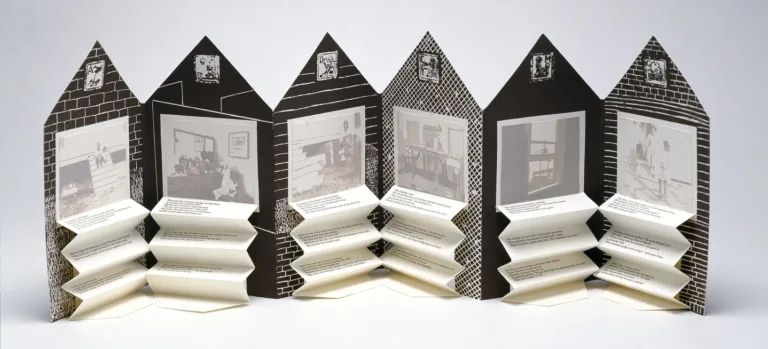 An open accordion-style book in the shape of a house. On each page is a black and white graphic background and a washed-out black and white photograph. Beneath each image is typed text on accordion folded paper.
