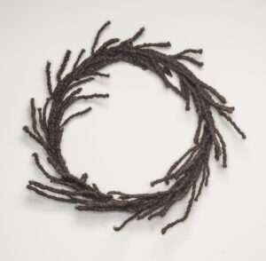 A circular wreath made of tightly coiled hair with strands escaping.