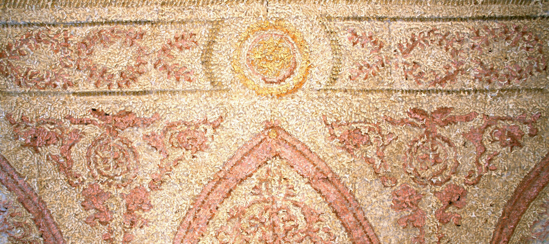 A colored image of what appears to be a wall decorated with mosaics in red and yellow tones. Upon closer inspection each shape is actually an origami bug.