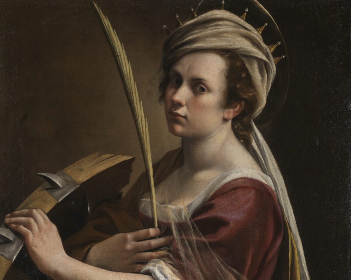 Against a dark black and brown background, a light skinned woman in a red dress with wavy reddish-brown hair wears a white cloth and gold crown around her head. Her right hand clutches a palm while her left grazes a spiked breaking wheel. She stares straight at the viewer.