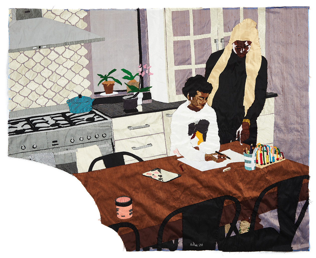 In a grey modern kitchen, a dark skinned mother stands beside her son, who is seated with a pen and paper in his hands. Behind them, an orchid sits on the counter and a small blue pot sits on the stove.