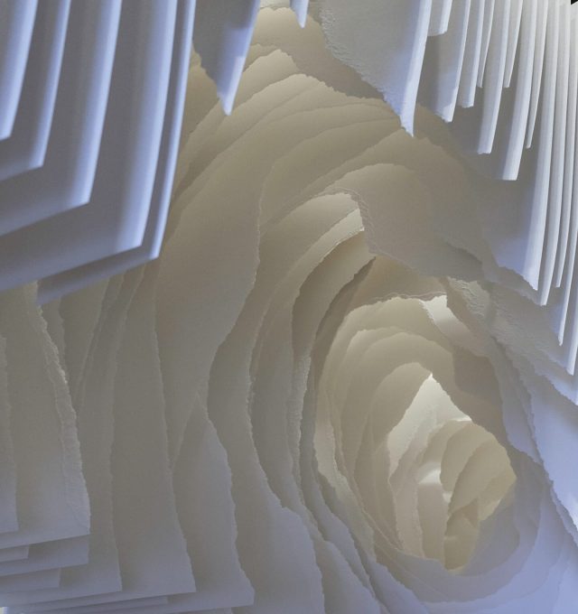 Detail view of torn sheets of white paper that can be looked through like a tunnel with pieces of paper blocking the view.