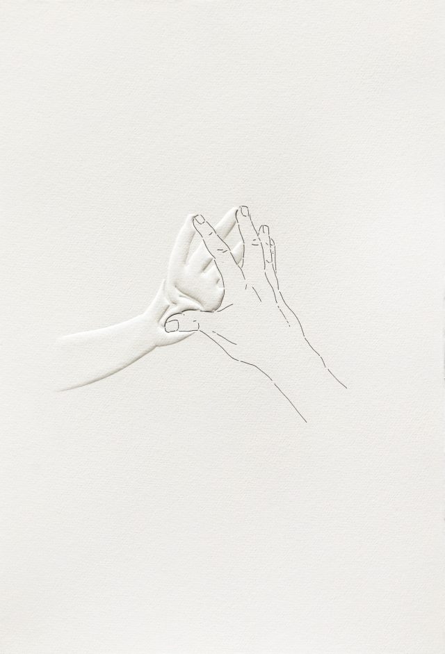 An image of two hands touching by their fingertips. The back of one hand is drawn on the paper and the palm of the other is embossed.