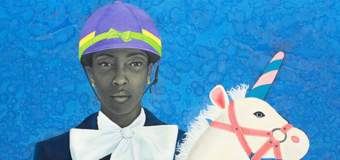 Portrait of a young woman with medium-dark skin tone rendered in grayscale set against a vibrant blue background. She wears horseback riding attire along with playful elements like a multicolored helmet and oversized bow; she holds a child's stick unicorn in her hand.