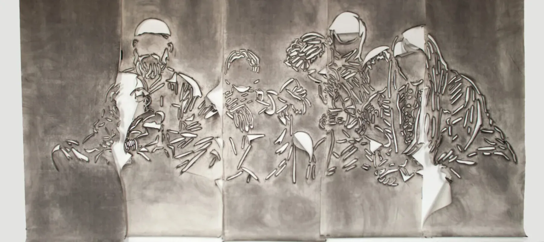 Five panels of paper covered in gray charcoal in which there is a cut stencil of an image of a group of faceless people. The panels have portions of paper that flap and fold.