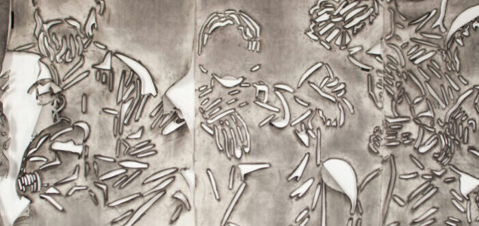 Five panels of paper covered in gray charcoal in which there is a cut stencil of an image of a group of faceless people. The panels have portions of paper that flap and fold.