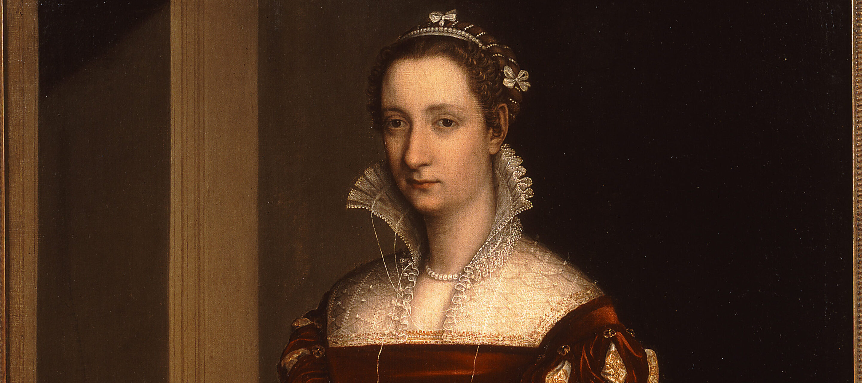 Three quarter length painting of a woman standing against a dark background. She is wearing a sumptuous red Renaissance-style dress with a high lace collar. Standing next to her at bottom left is a child holding a small spaniel.