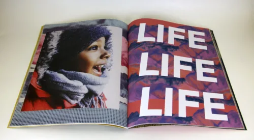 Open book features photograph of a child with medium-brown skin on the left side of the fold and the words "LIFE LIFE LIFE" filling the page on the right.