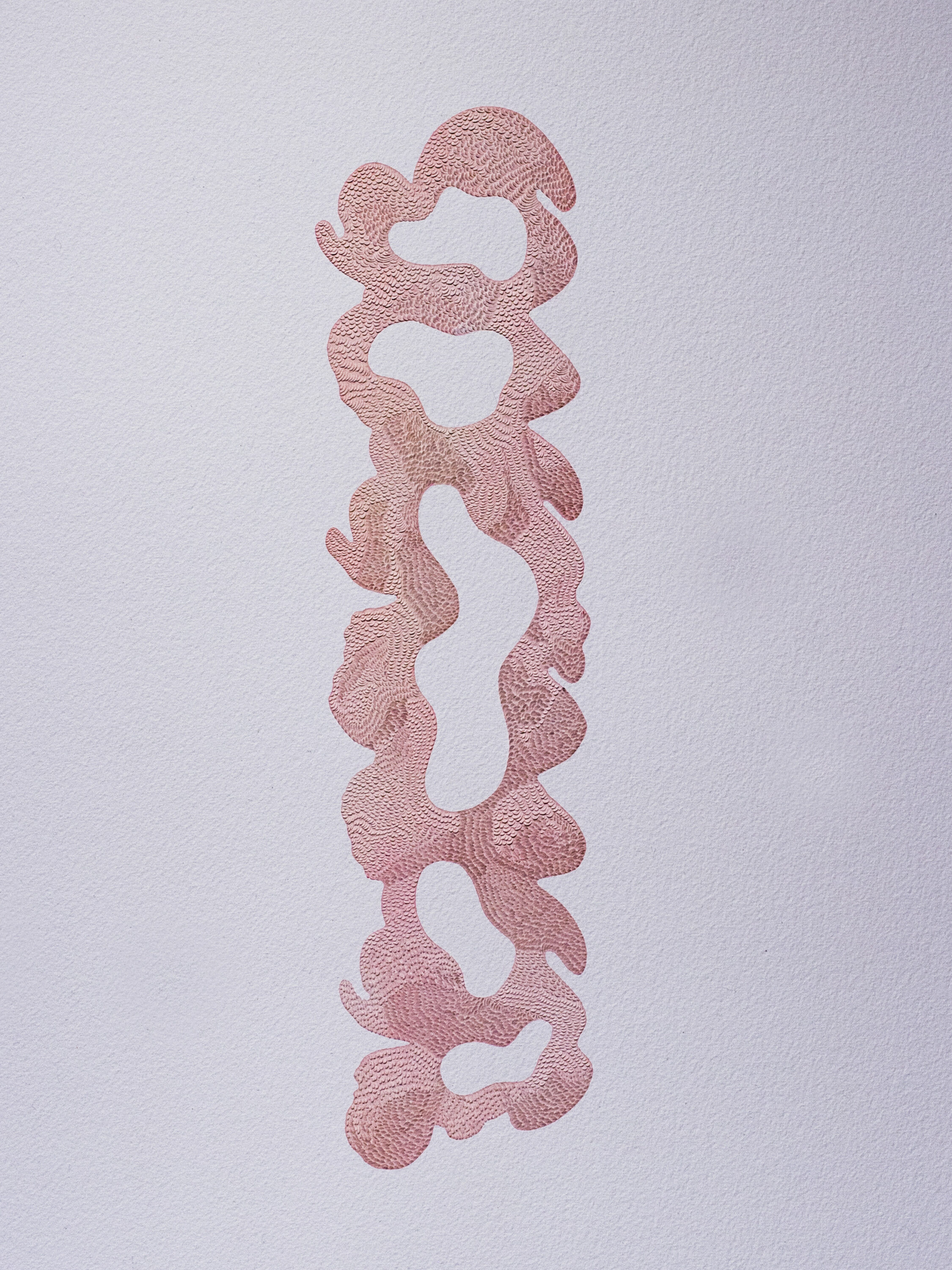A long, vertical abstract column in a pinkish-red hue is made out of individual cuts to a piece of paper. The shape has wavy, soft, organic edges. 