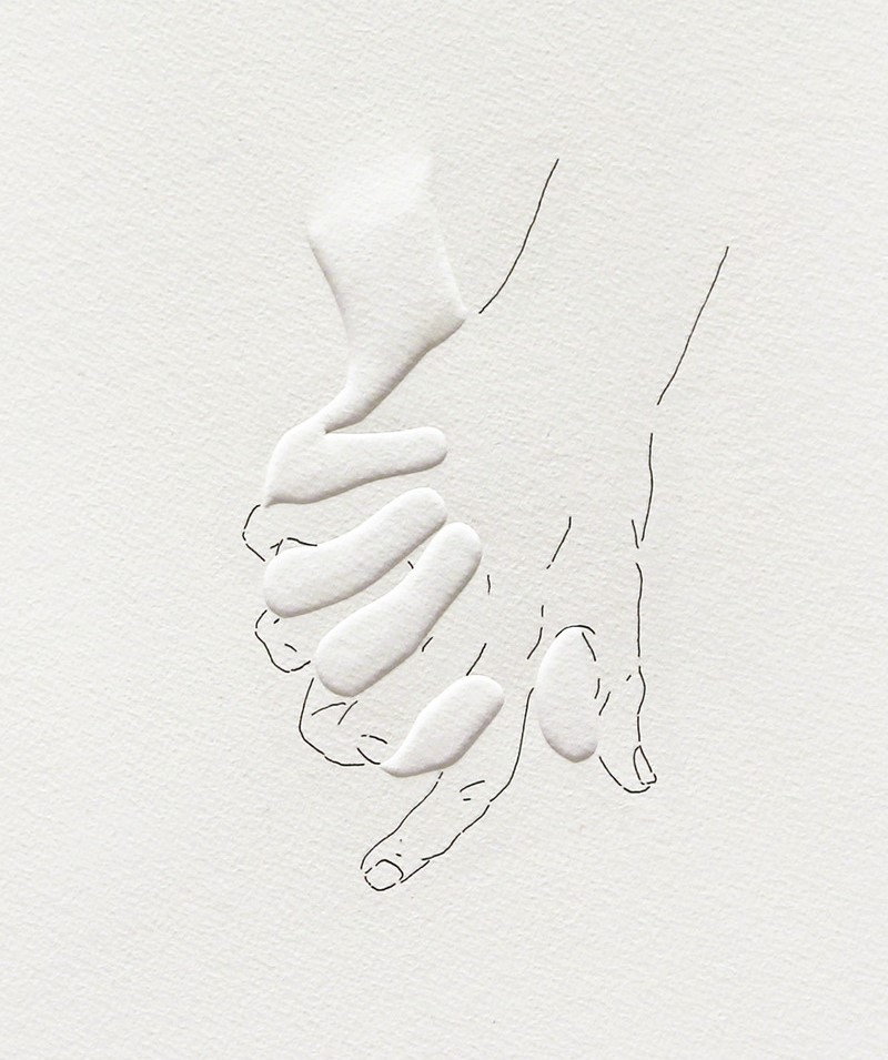 An image of two hands clasped with interlacing palms. The back of one hand is drawn on the paper and the fingers of the other is embossed.