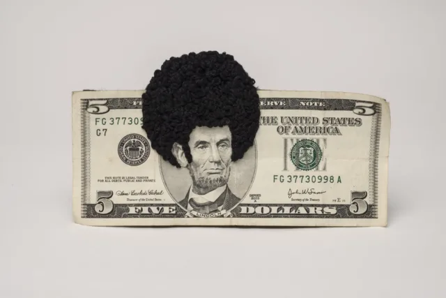 U.S. five-dollar bill has an embroidered afro and sideburns stitched onto the portrait of Lincoln’s head. One-third of the afro protrudes beyond the top of the bill.