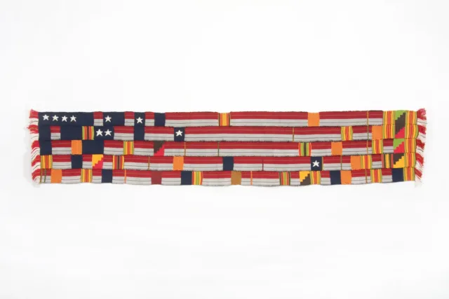 A horizontal, rectangular fabric artwork, made of woven strips of silk and cotton. The colors of the horizontal fabric strips are red, white, and blue, reminiscent of the American flag, while interwoven the vertical strips are shades of yellow, orange and green.