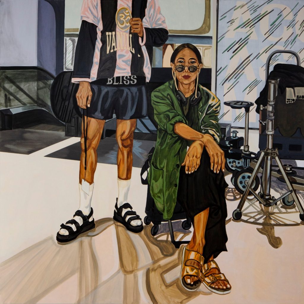 A figurative painting of a woman of Asian descent seated on a low chair with her legs crossed; she looks confidently at the camera from behind stylish sunglasses that sit low on her nose. Behind her a male figure stands, though his head is cropped. He wears athletic-looking clothing and socks and sandals. An escalator is in the background behind them.