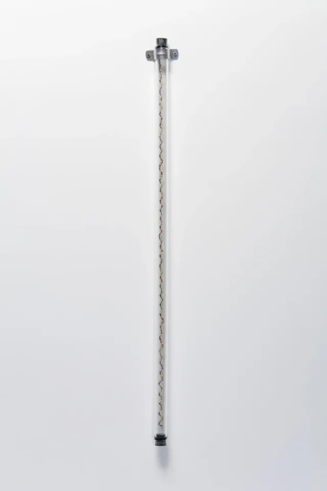 A sculpture of a glass tube affixed to a white wall with a spiraling column of small, multicolored glass beads. The beads are blue, red, yellow, green and black.