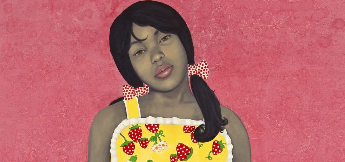 Wearing a bright yellow apron-style dress with strawberries and lace-trim details, an expressionless young woman with medium-dark skin tone rendered in grayscale stares out with her hands in her dress pockets. Her head is cocked to one side against an intensely pink-colored background.