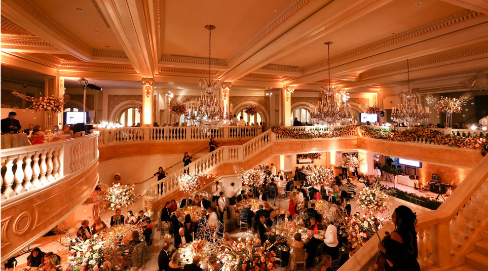 Overview of the Great Hall shot from the Mezzanine balcony looking down at a festive party with tables and guests.