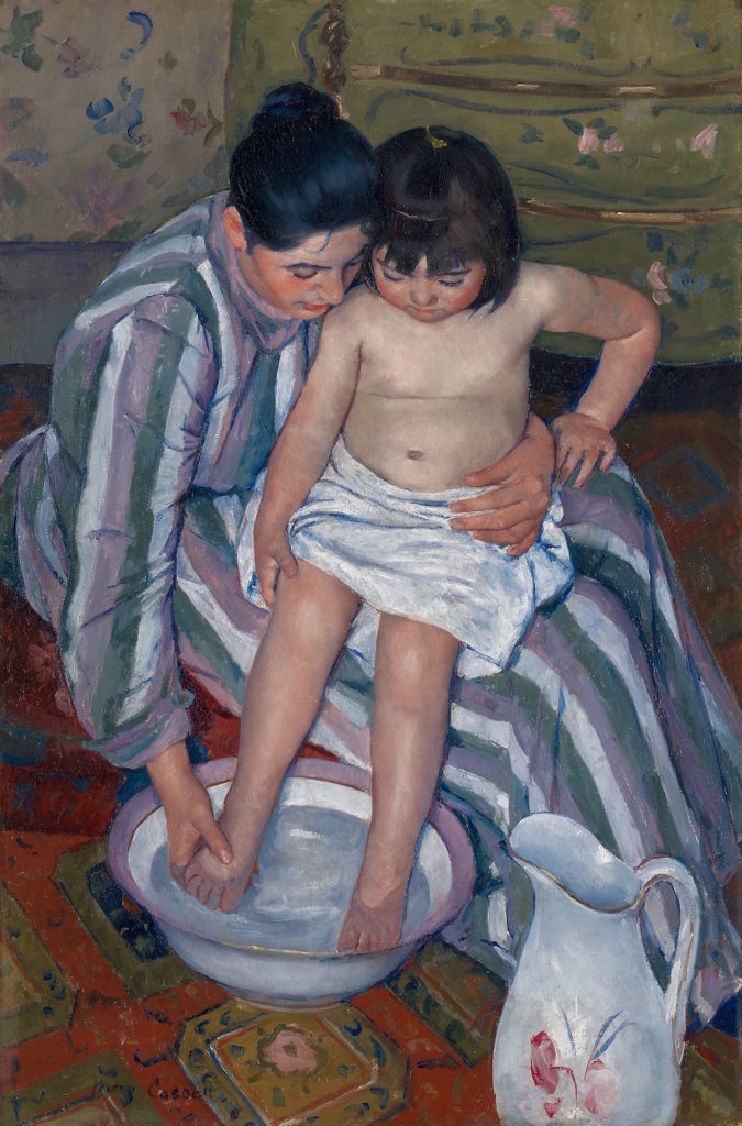 A painting of a light-skinned woman with black hair pulled back in a bun, wearing a long-sleeved striped dress, with a light-skinned little girl on her lap. The girl is nude, except for a white towel around her waist, and the older woman washes the girl's feet in a large porcelain bowl filled with water.