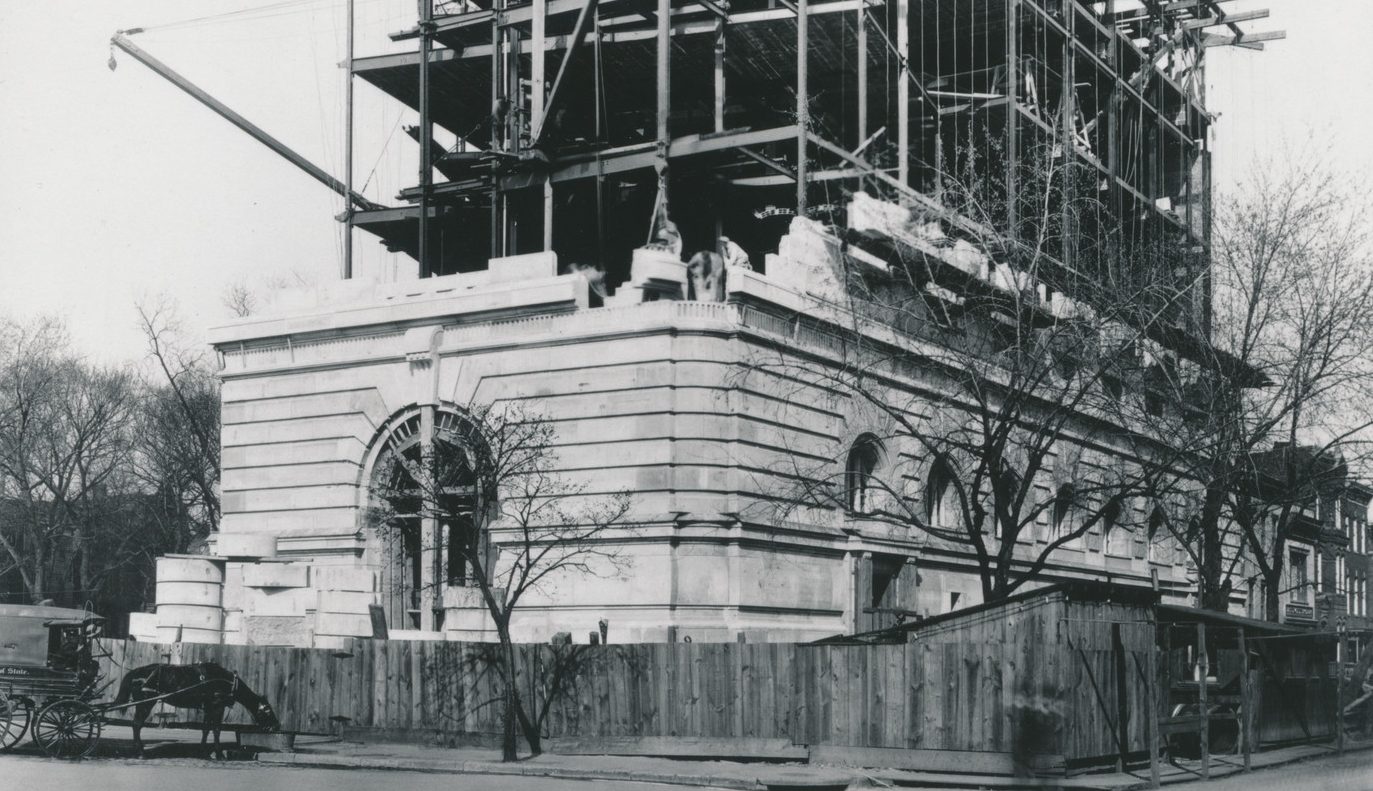 Black and white photograph showing the construction of the museum's building from early 20th century. The bottom floors are partially bricked while the upper floors only have scaffolding.