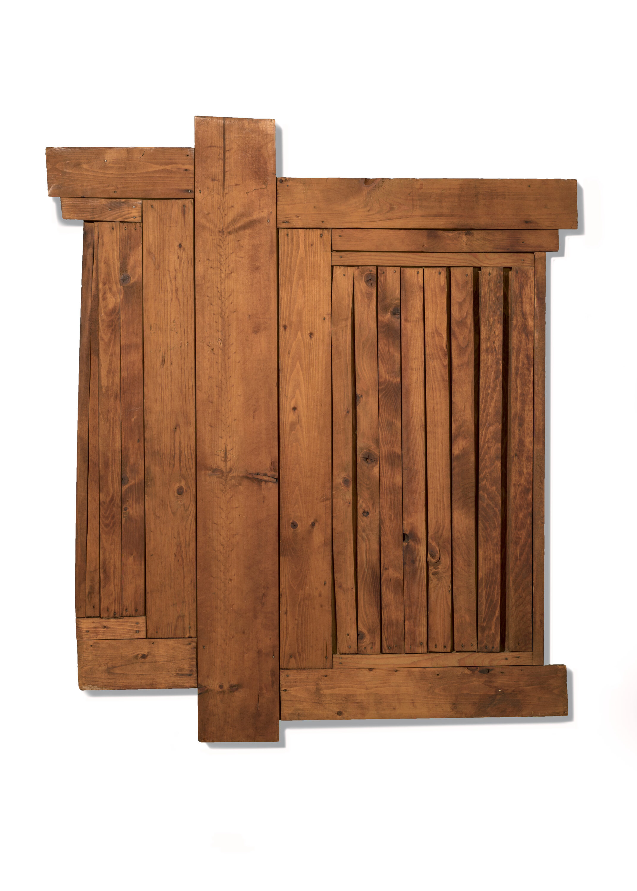 A square sculpture made out of planks of wood is hung against a white wall. The planks are hung vertically next to one another and come in differing widths. There are a few horizontal planks hung at the top and bottom of the piece, mimicking a border.