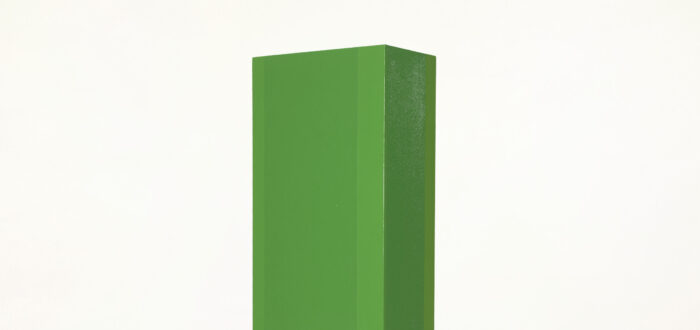 Tall, rectangular, pillar-like sculpture, painted in vibrant green hues on a smooth, clean surface. The sculpture stands against a solid white backdrop.