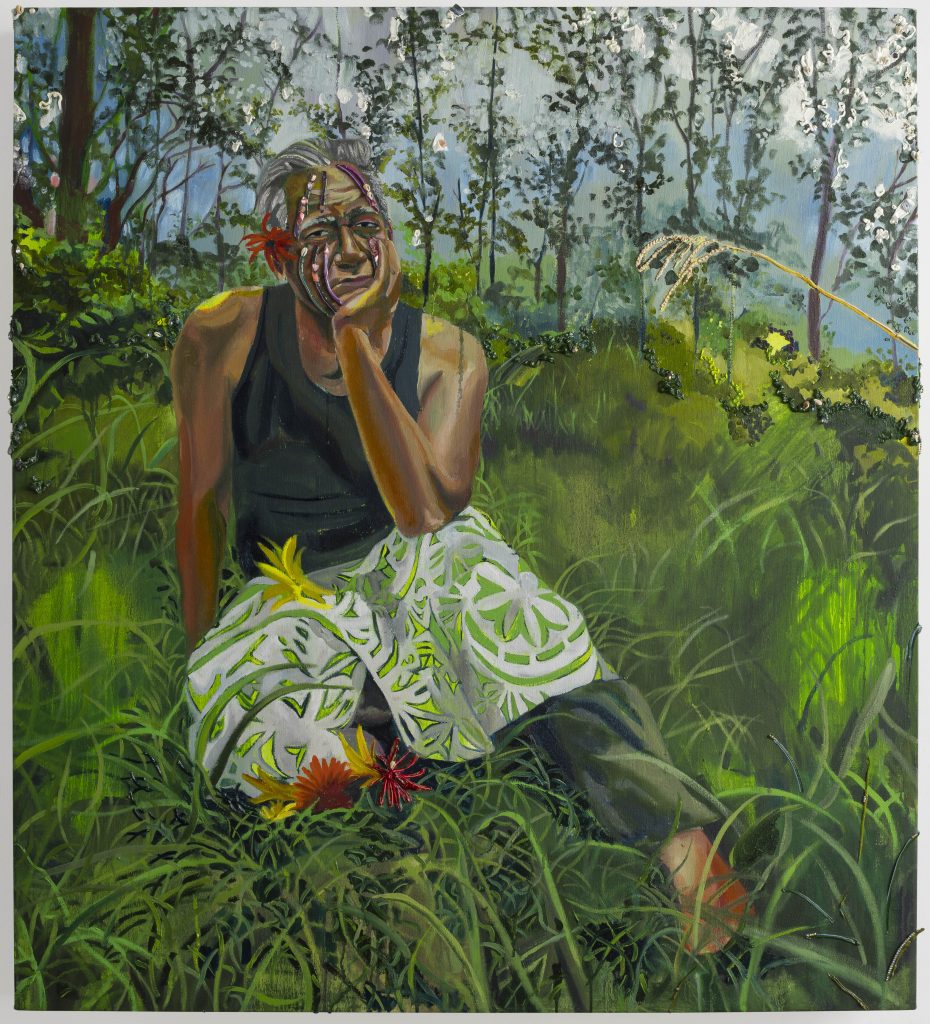 A figurative painting features an older indigenous woman with short, grey hair sitting in a lush gree tropical forest. Sunlight dapples some patches of the grass. She rests one hand on her chin, while the other is set on the ground behind her. She wears a solemn expression.