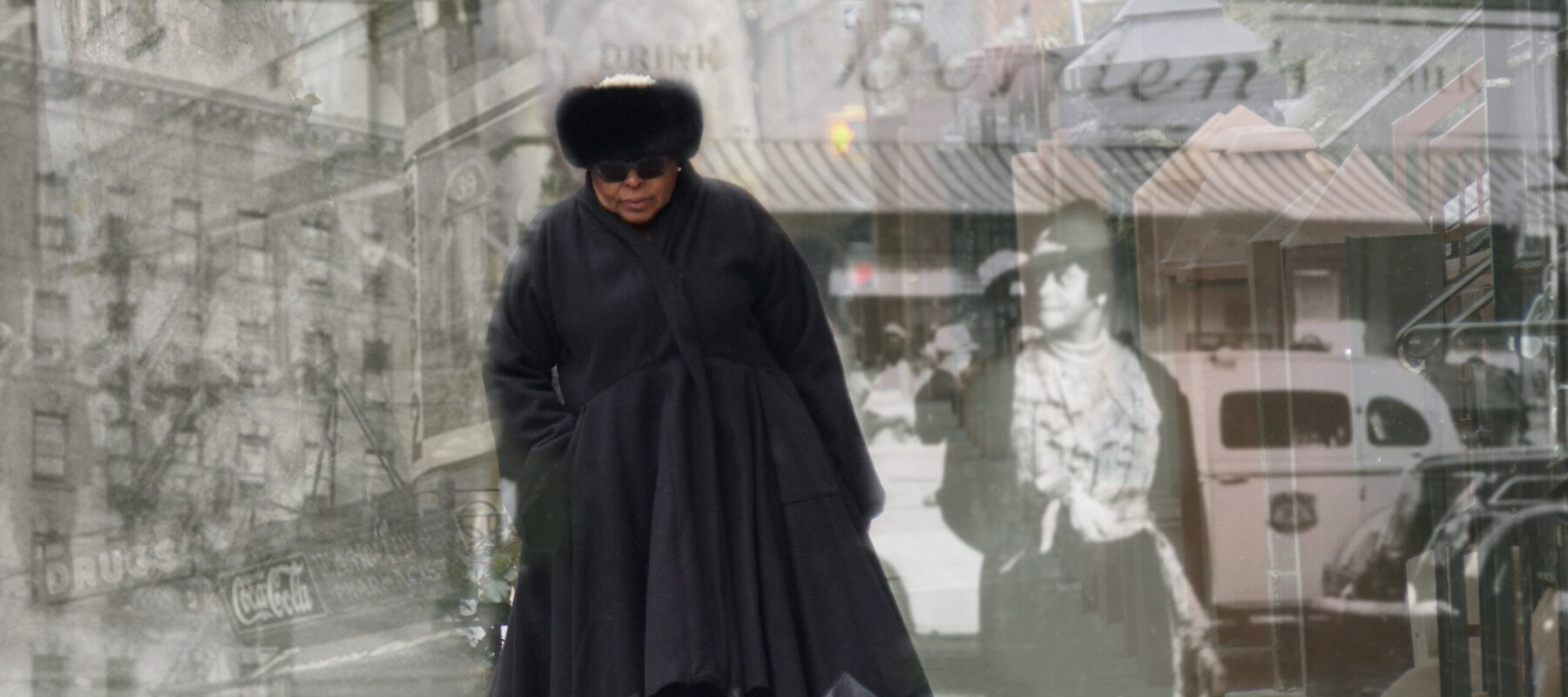 A medium-dark skinned adult woman wearing all black—a fur hat, sunglasses, boots, and a long, voluminous coat—walks on a sidewalk toward the viewer. Black and white images of people and buildings in Harlem from the early 20th century are layered over the woman.